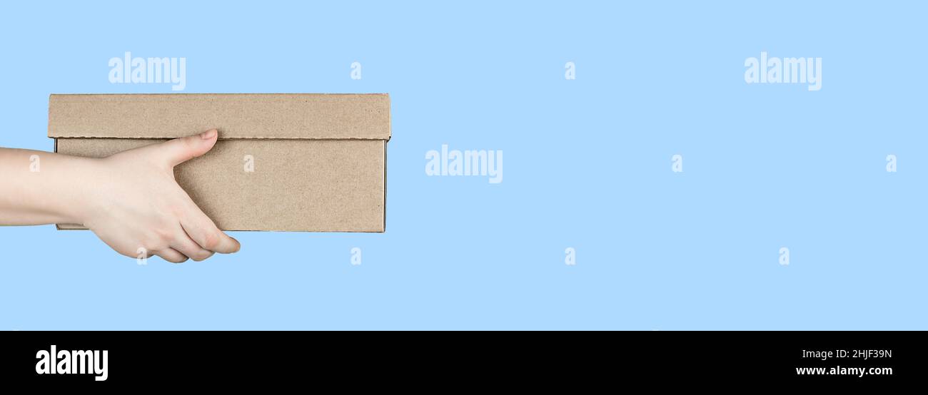 Large cardboard box in hands on blue background Stock Photo