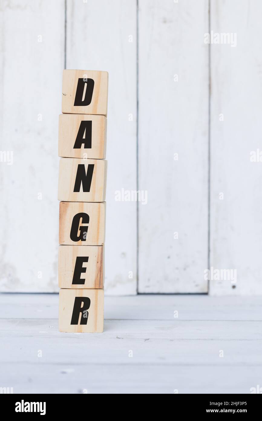 wooden cube, with the word danger, with white wooden background Stock Photo