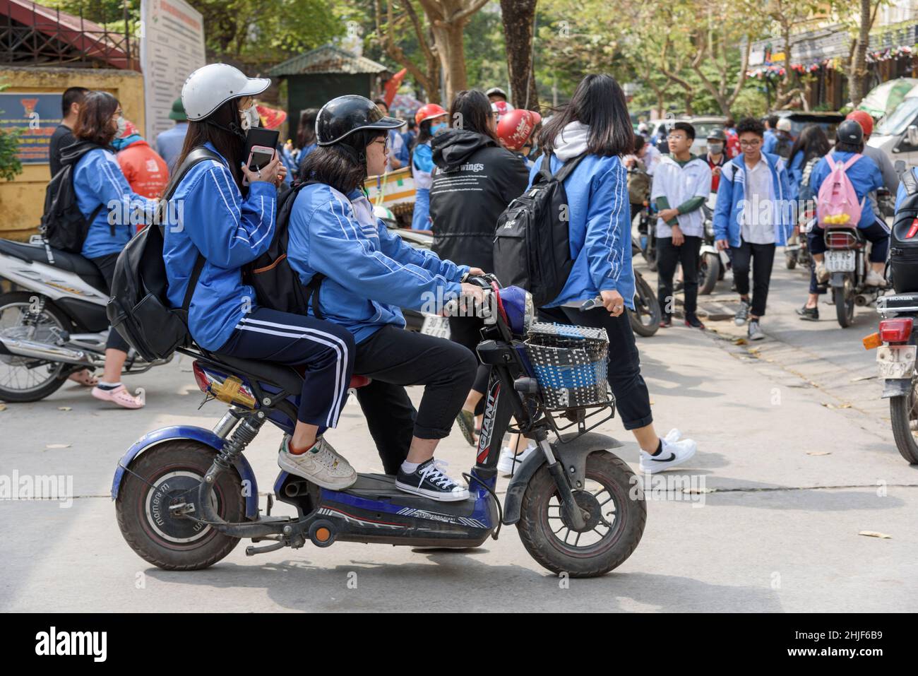 Vietnamese schoolchildren, wearing their blue uniforms, leave school at