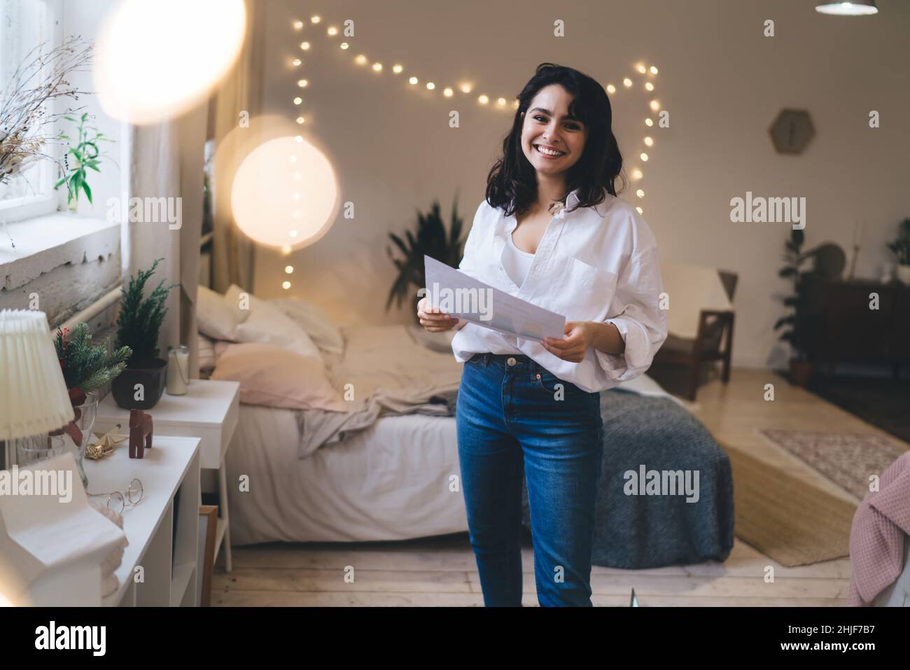 Positive woman with document standing in bedroom Stock Photo