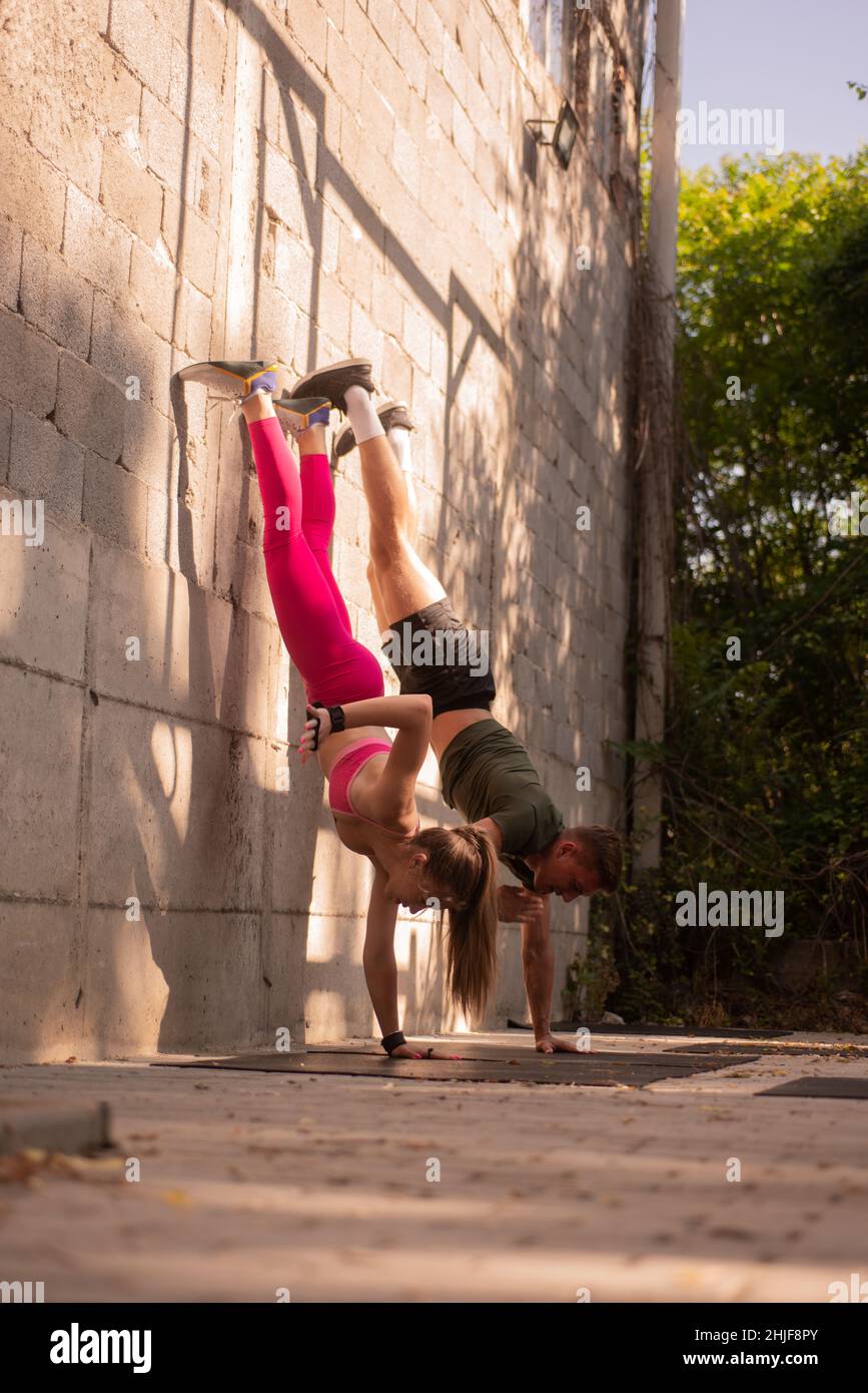 Couple is exercising while being upside down and balanicng on one arm ...