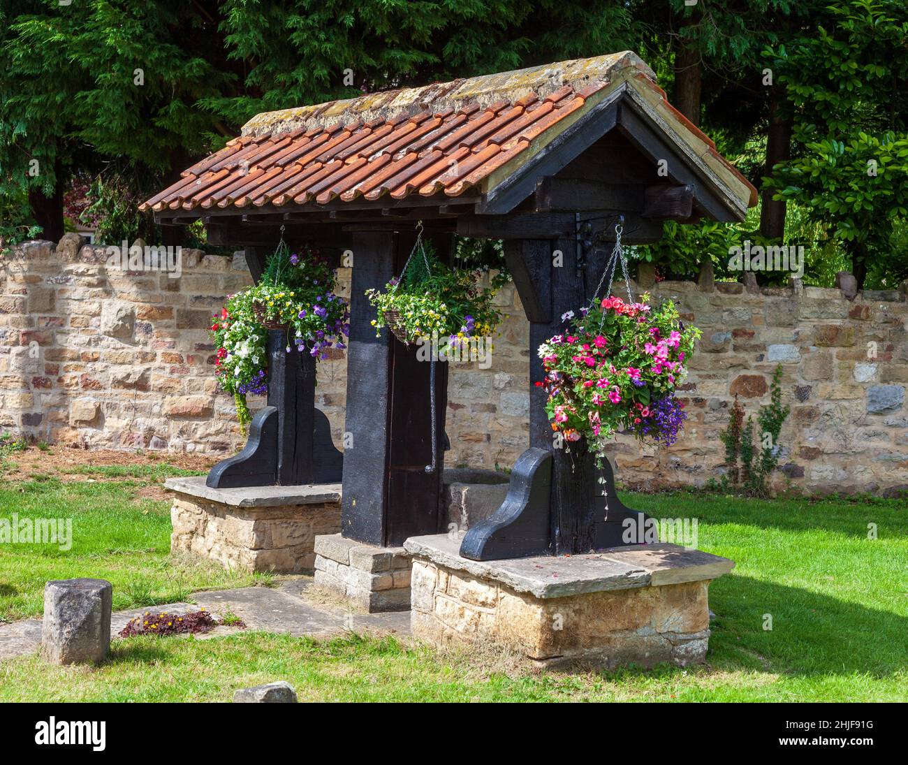 The village pump decorated with flowers on the green in Linton, West Yorkshire Stock Photo