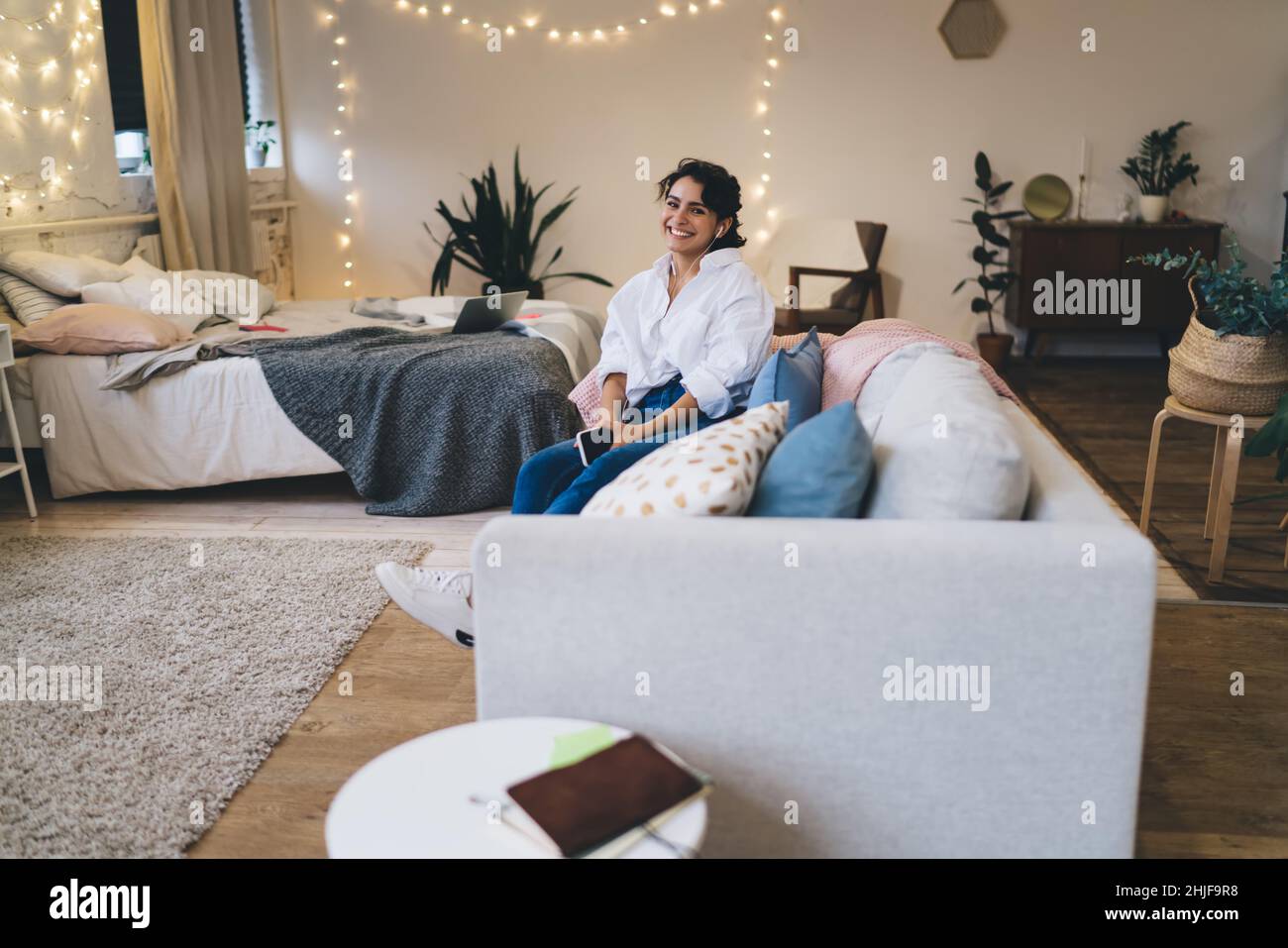 Smiling woman resting on sofa in cozy bedroom Stock Photo