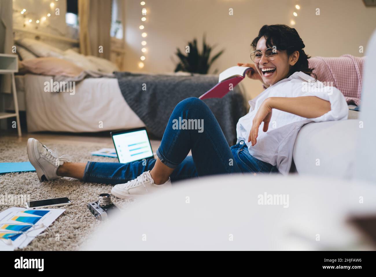 Positive young woman in eyeglasses using laptop while working Stock Photo