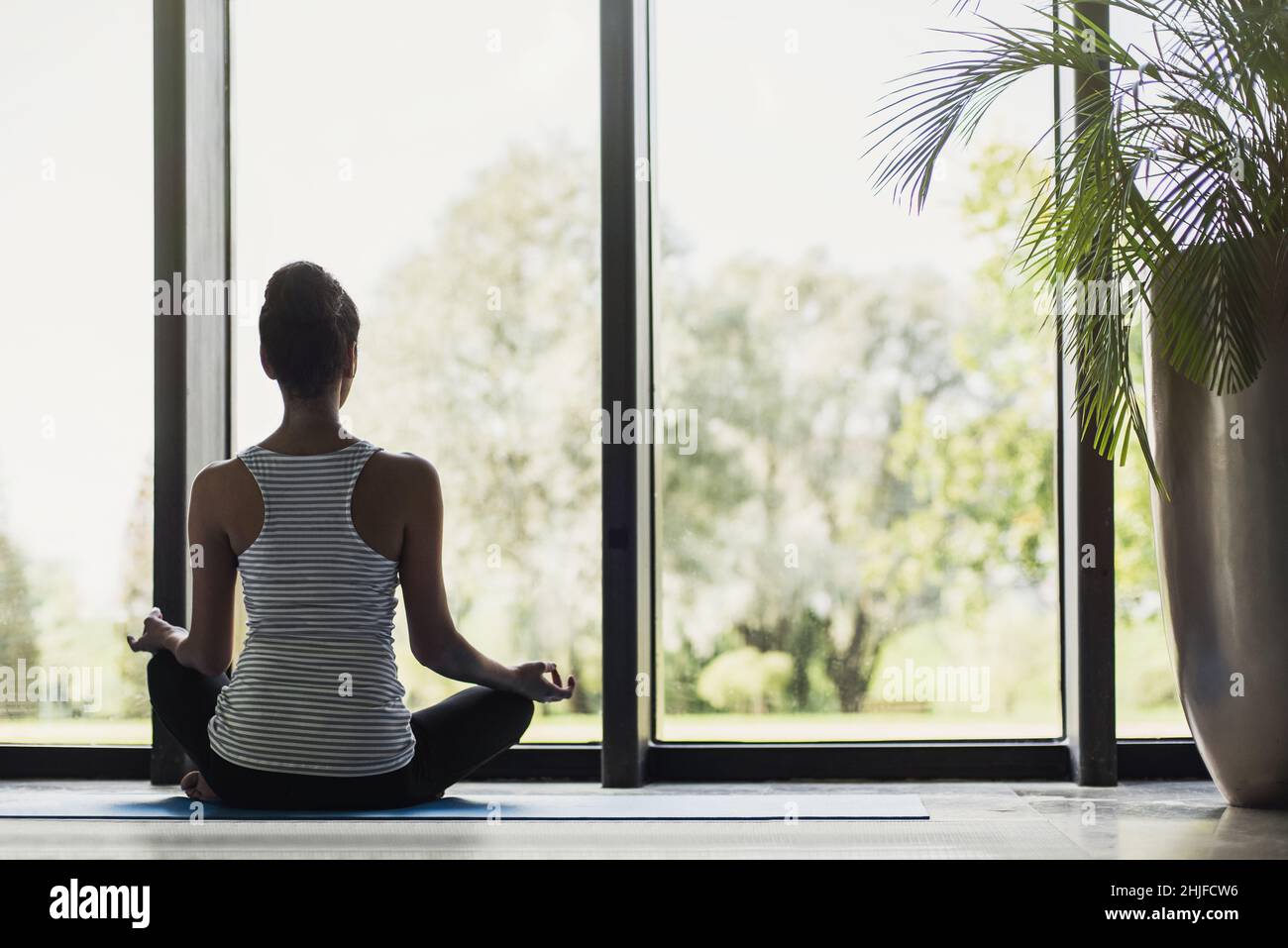 Young woman meditating at home. Girl practicing yoga in class. Healthy lifestyle, meditation, mindfulness, recreation, self care concept Stock Photo