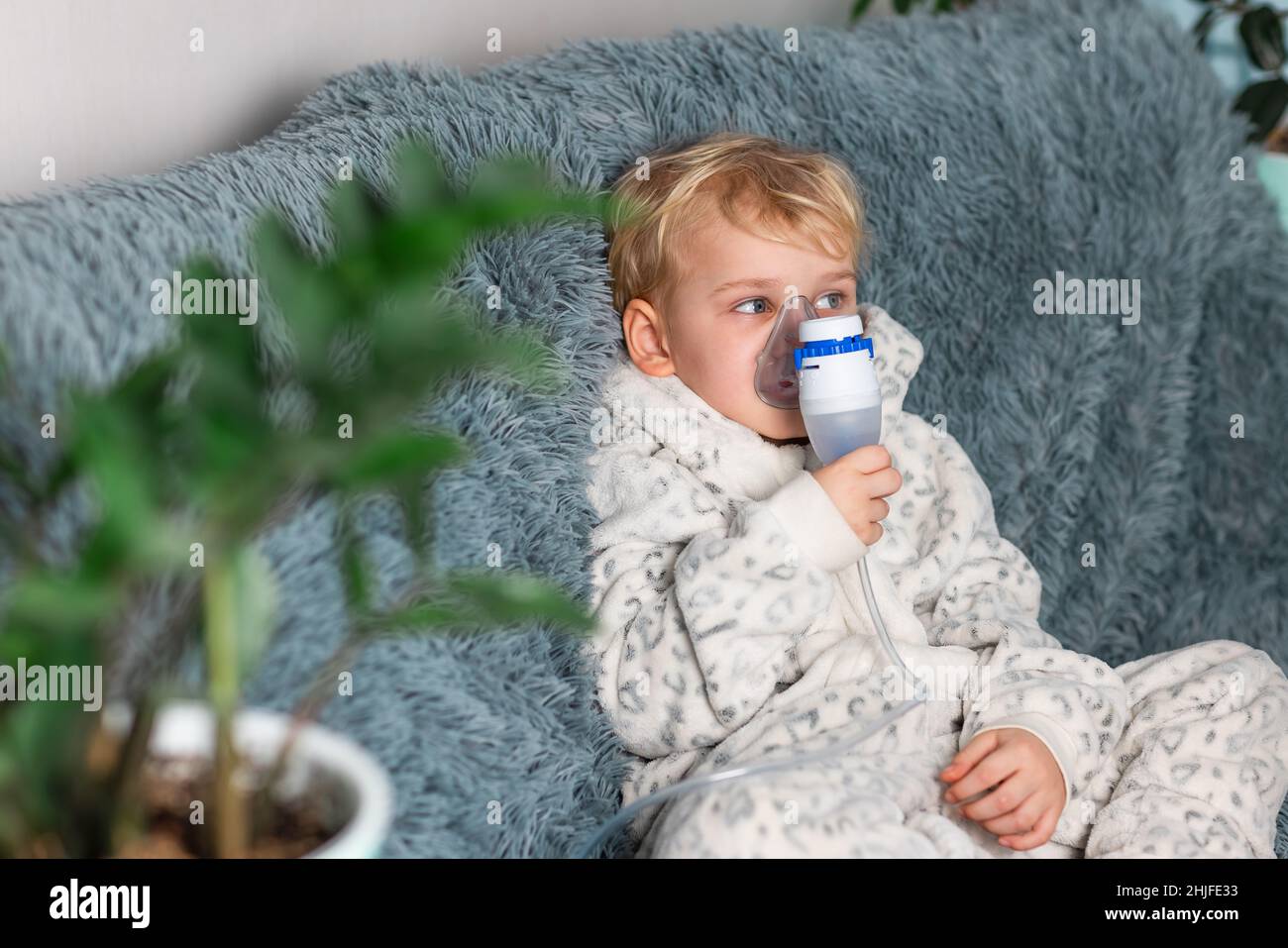 Cute baby boy makes inhalation with a nebulizer equipment. Sick child