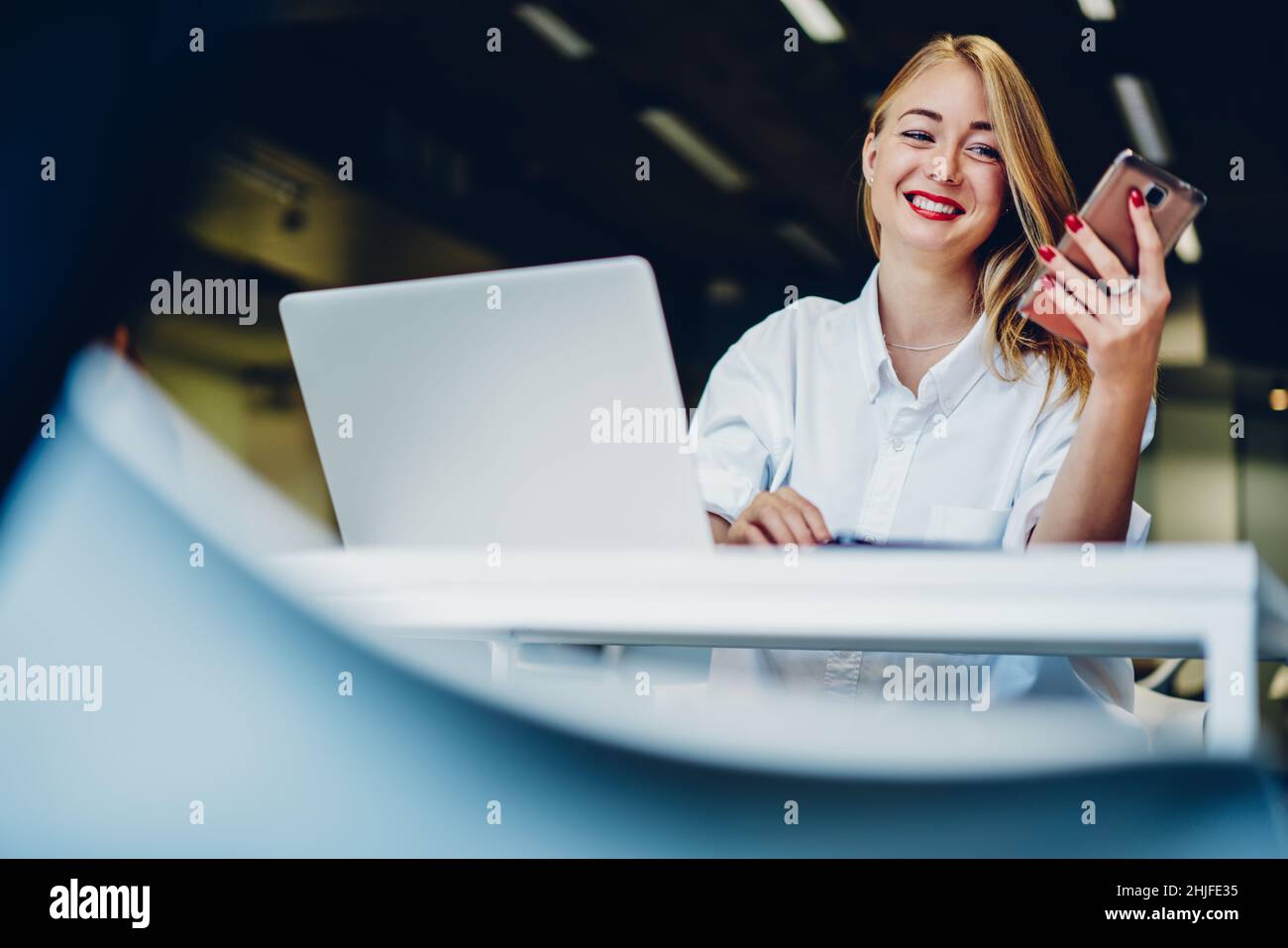 Smiling remote worker using phone and laptop Stock Photo