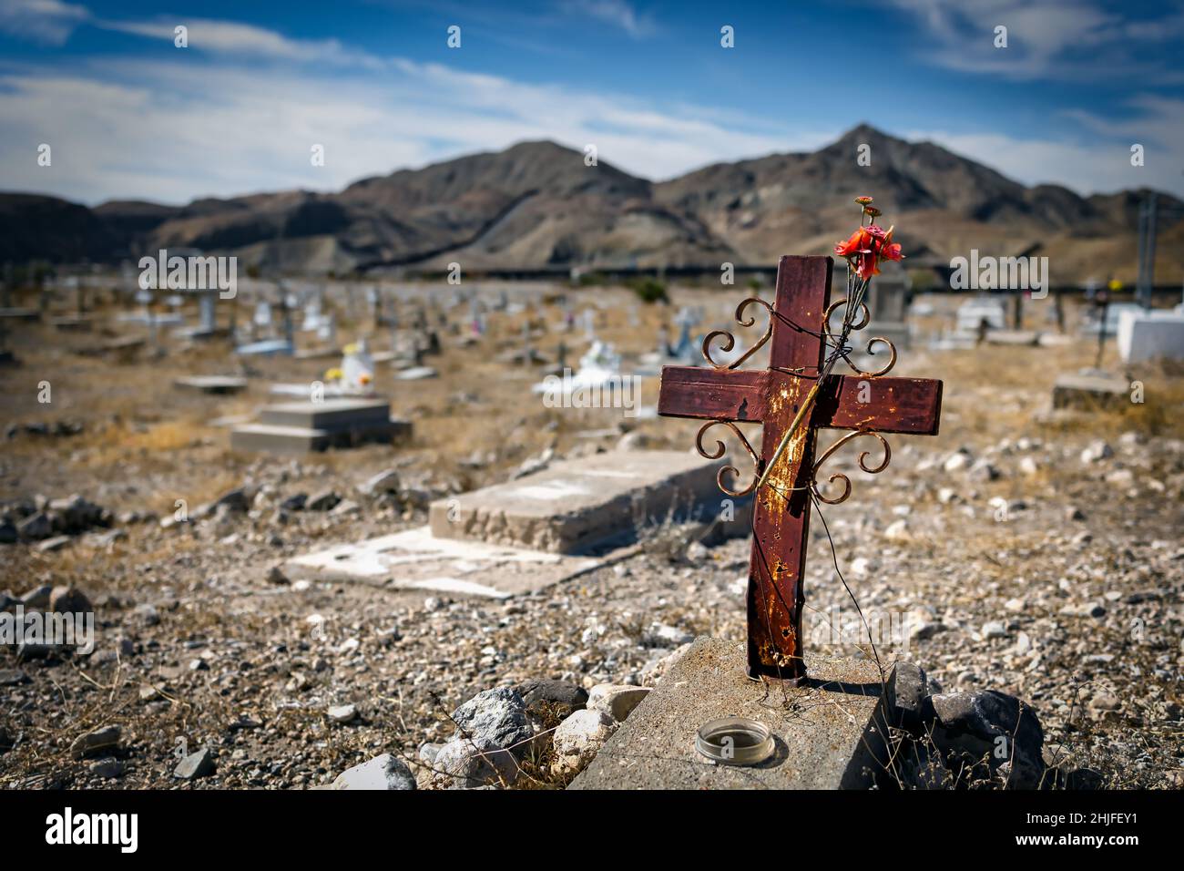 An old metal cross with a plastic flower sits at the old west