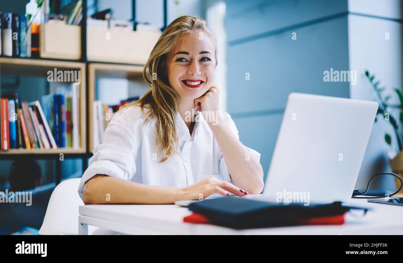 Smiling woman with laptop in workspace Stock Photo