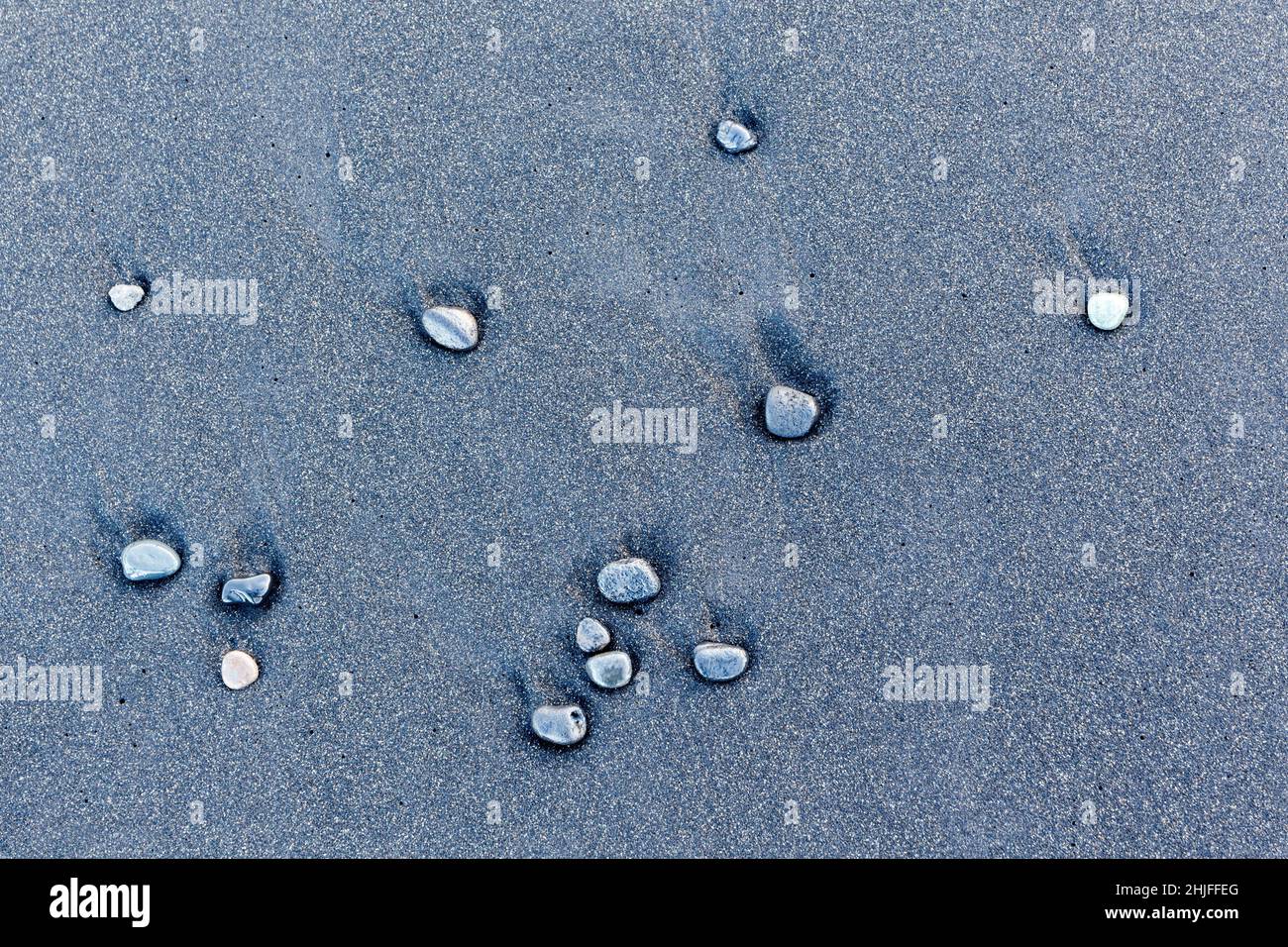 Small wet pebbles on a beach of volcanic sands Stock Photo