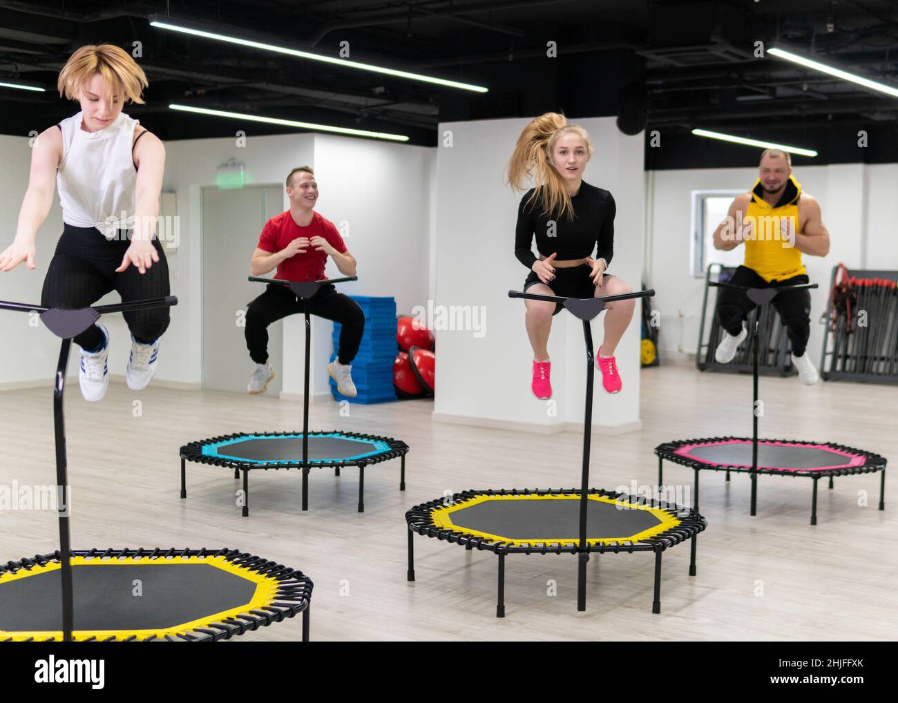 Jumping on a trampoline in fitness four on colored ski jumps sports  equipment, the concept of a healthy lifestyle, a cheerful company on a  white backg Stock Photo - Alamy