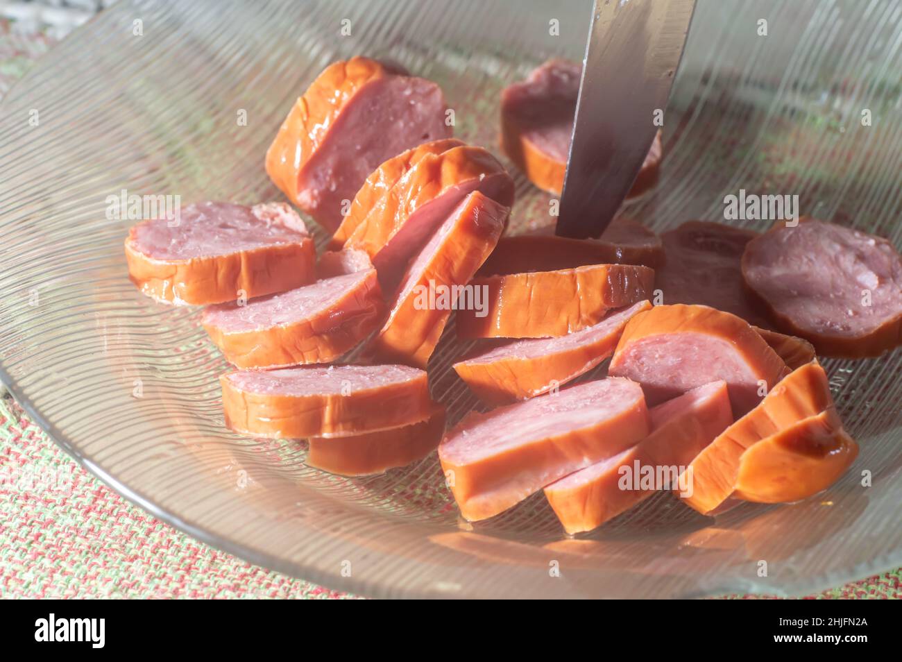 Calabresa sausage sliced on a plate with hand holding a slice,simple concept of cold cuts,Brazilian calabresa. Stock Photo