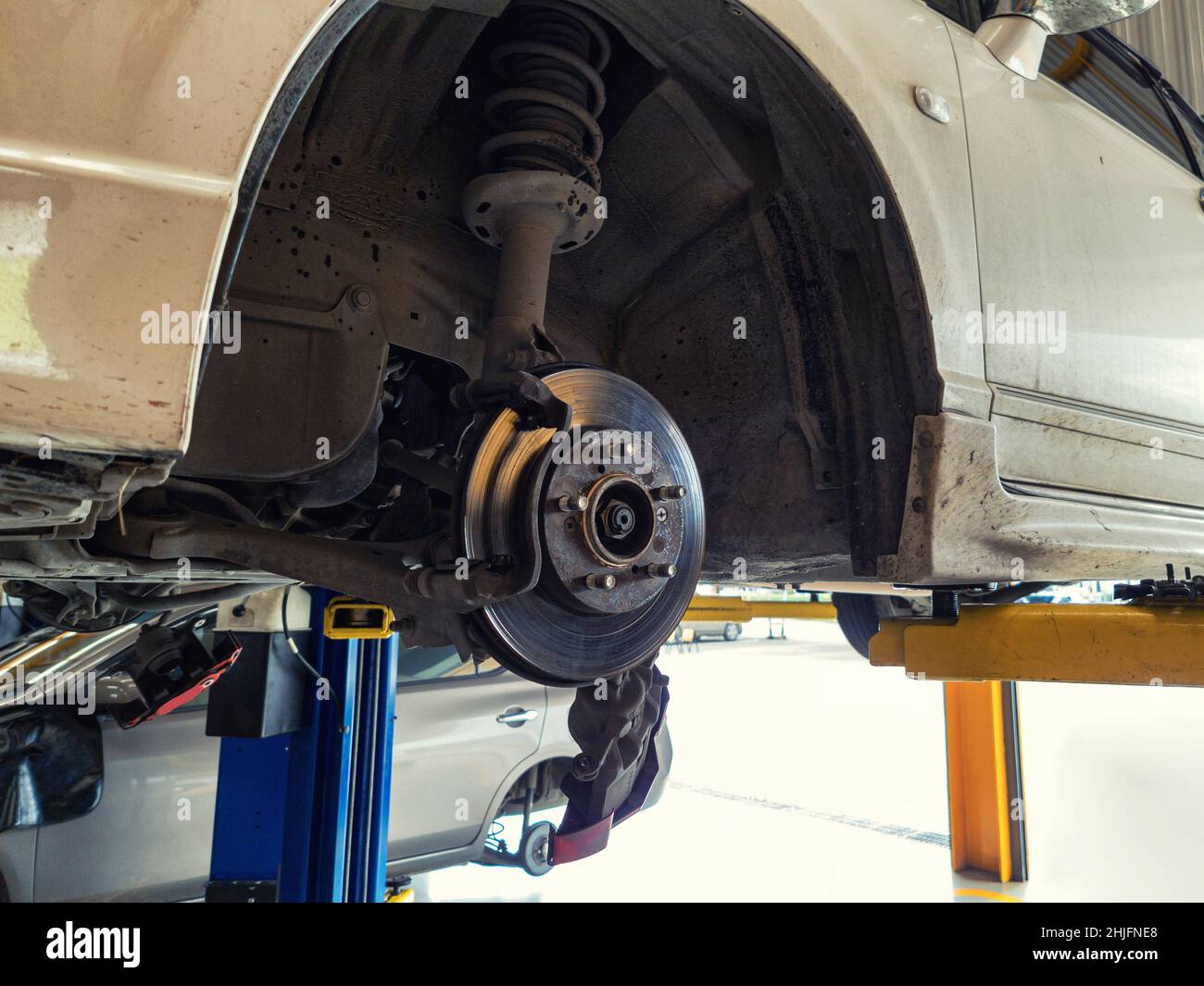 Damaged car and dirty disc brake lifting for maintenance in garage