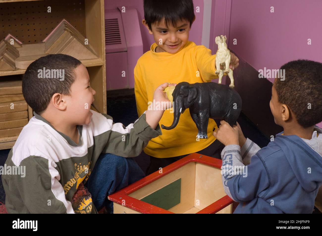 Education Preschool classroom ages 4-5 group of three boys playin together with toy animals, laughing and talking Stock Photo
