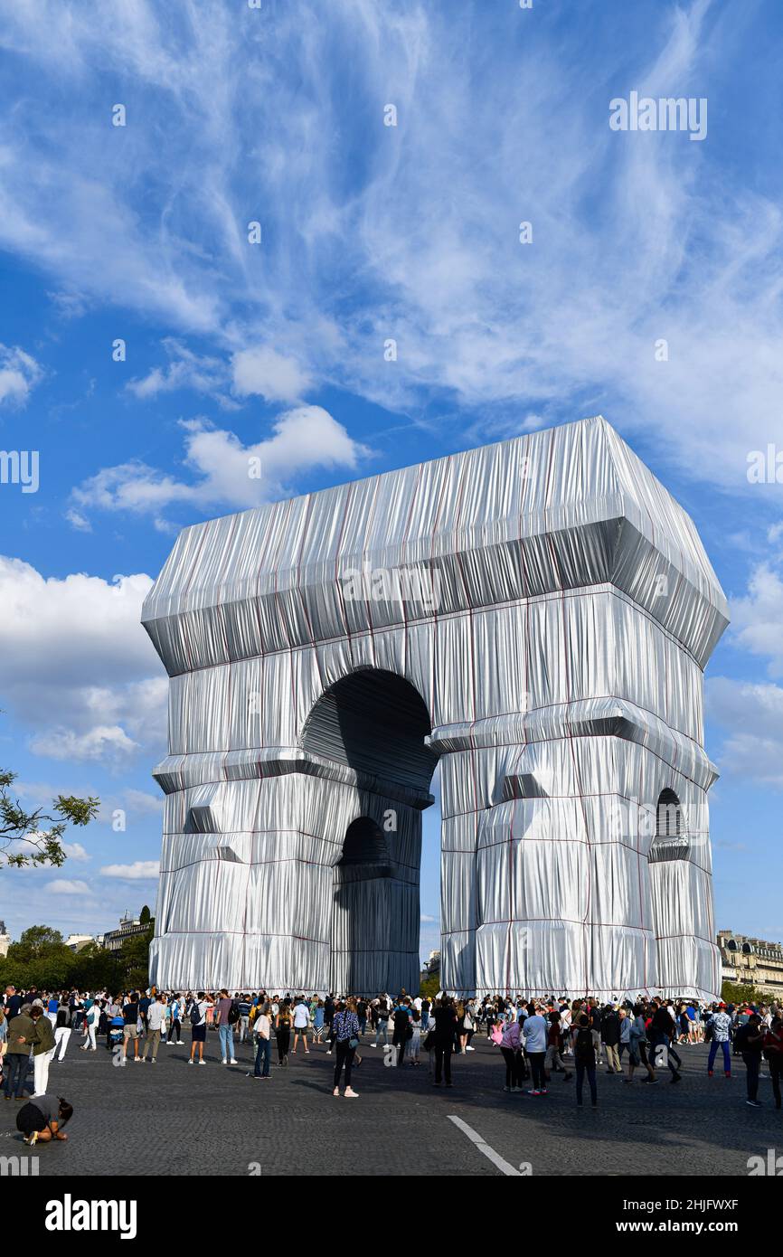 People looking at an art installation featuring the Arc de Triomphe (Arch of Triumph) wrapped in a giant sheet of fabric as part of a project of Bulga Stock Photo