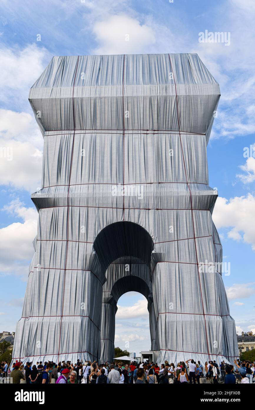 People looking at an art installation featuring the Arc de Triomphe (Arch of Triumph) wrapped in a giant sheet of fabric as part of a project of Bulga Stock Photo