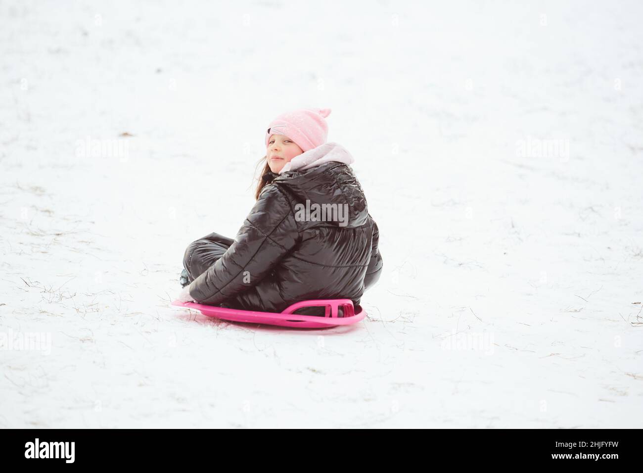 Happy little girl sliding down the hill on saucer sled. Girl enjoying ...