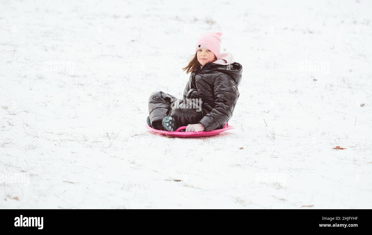 Happy little girl sliding down the hill on saucer sled. Girl enjoying ...