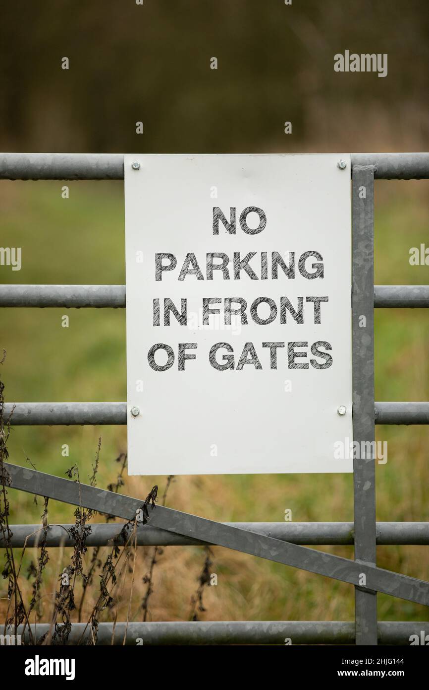 white sign with no parking in front of gates on a metal gate Stock ...