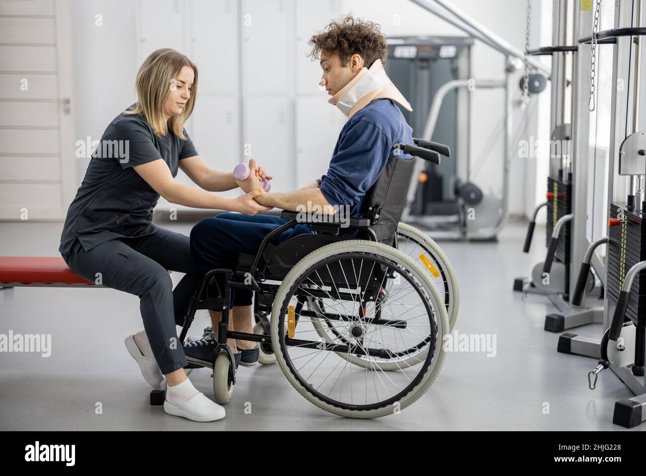Rehabilitation specialist with guy on a wheelchair doing exercise Stock