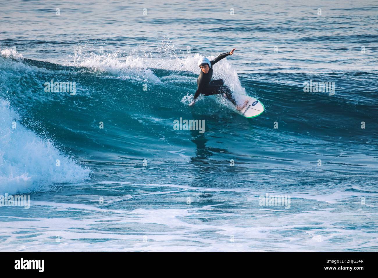 Surfer makes a maneuver in a perfect wave at the sunset Stock Photo