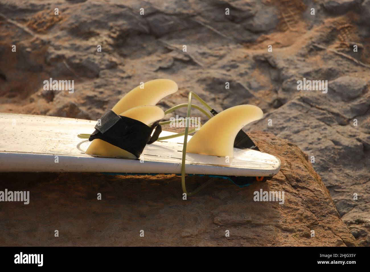 surfboard lays on the rocks from a surf spot Stock Photo