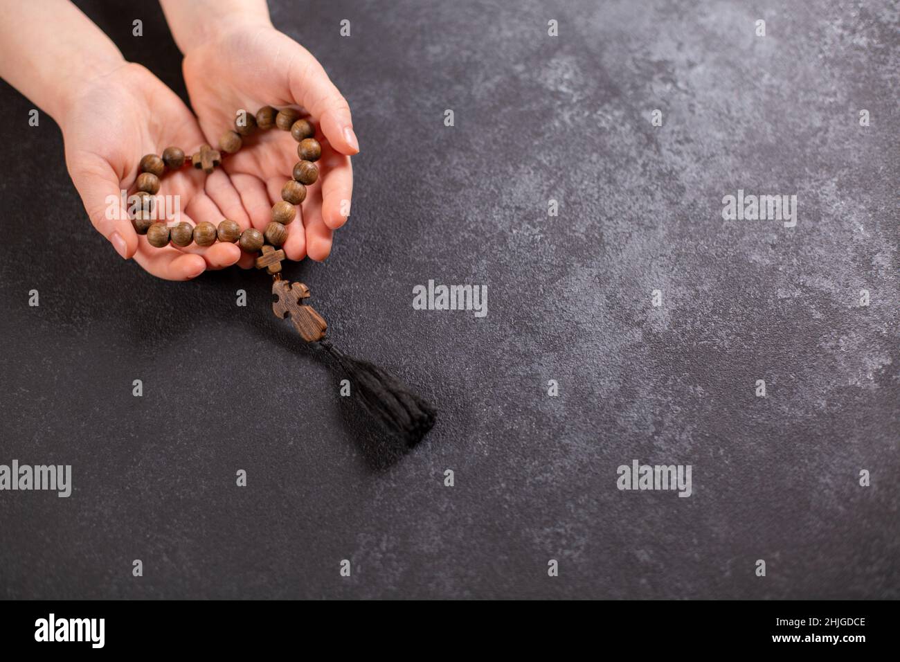 Child's hands holding the wooden cross and beads th in the shape of a heart. Top view. Flat lay