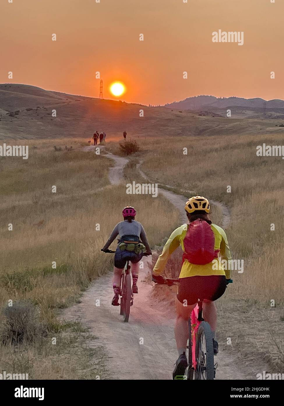 Mt bikers and hikers on foothill trails in the early morning under a smoke-tinged sun rise. Stock Photo