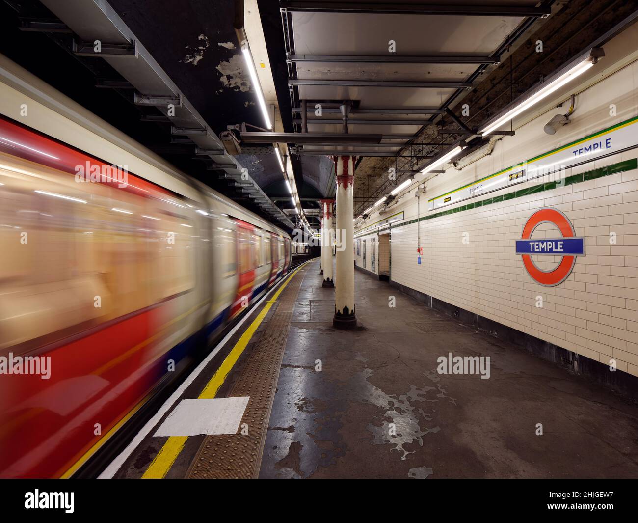 London, Greater London, England, January 5th 2022: Interior of Temple underground aka tube station as a train passes a platform with motion blur. Stock Photo
