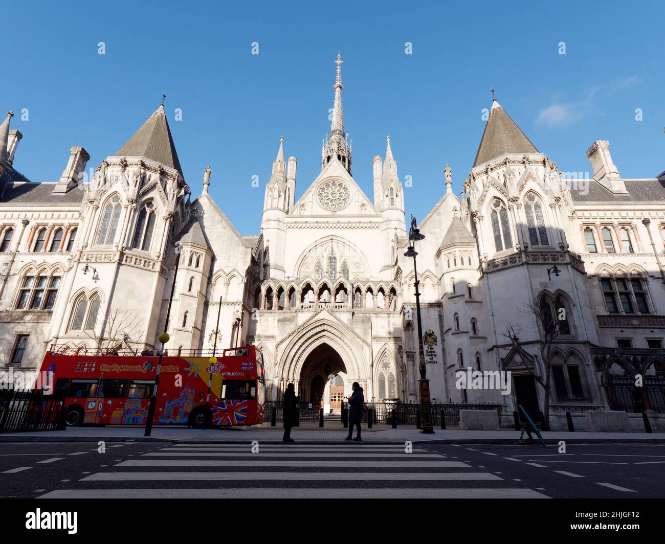 Open top sight seeing bus outside the Royal Courts of Justice on The Strand as pedestrians stand on a pedestrian crossing. London. Stock Photo