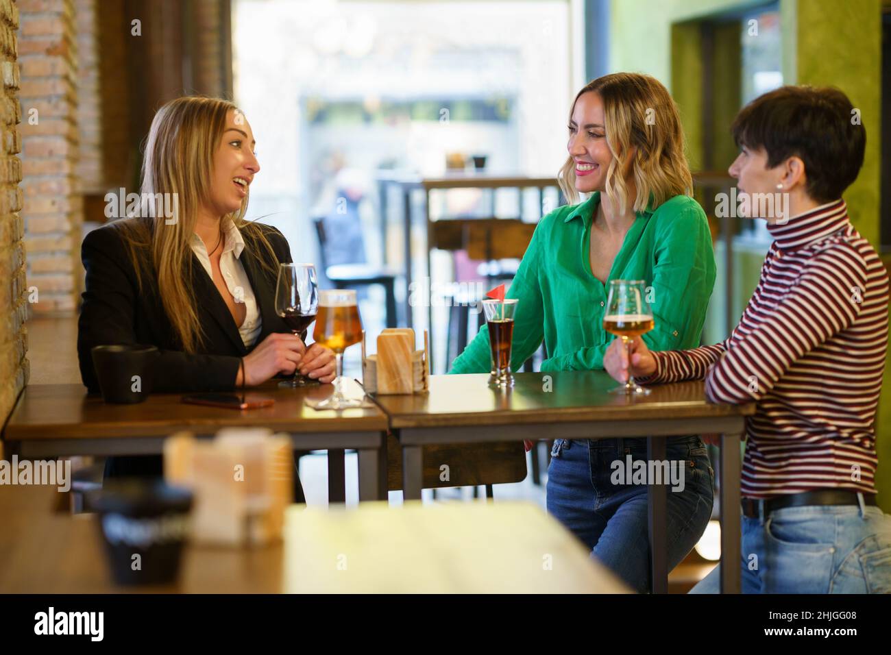 Cheerful girlfriends gathering around table in bar Stock Photo
