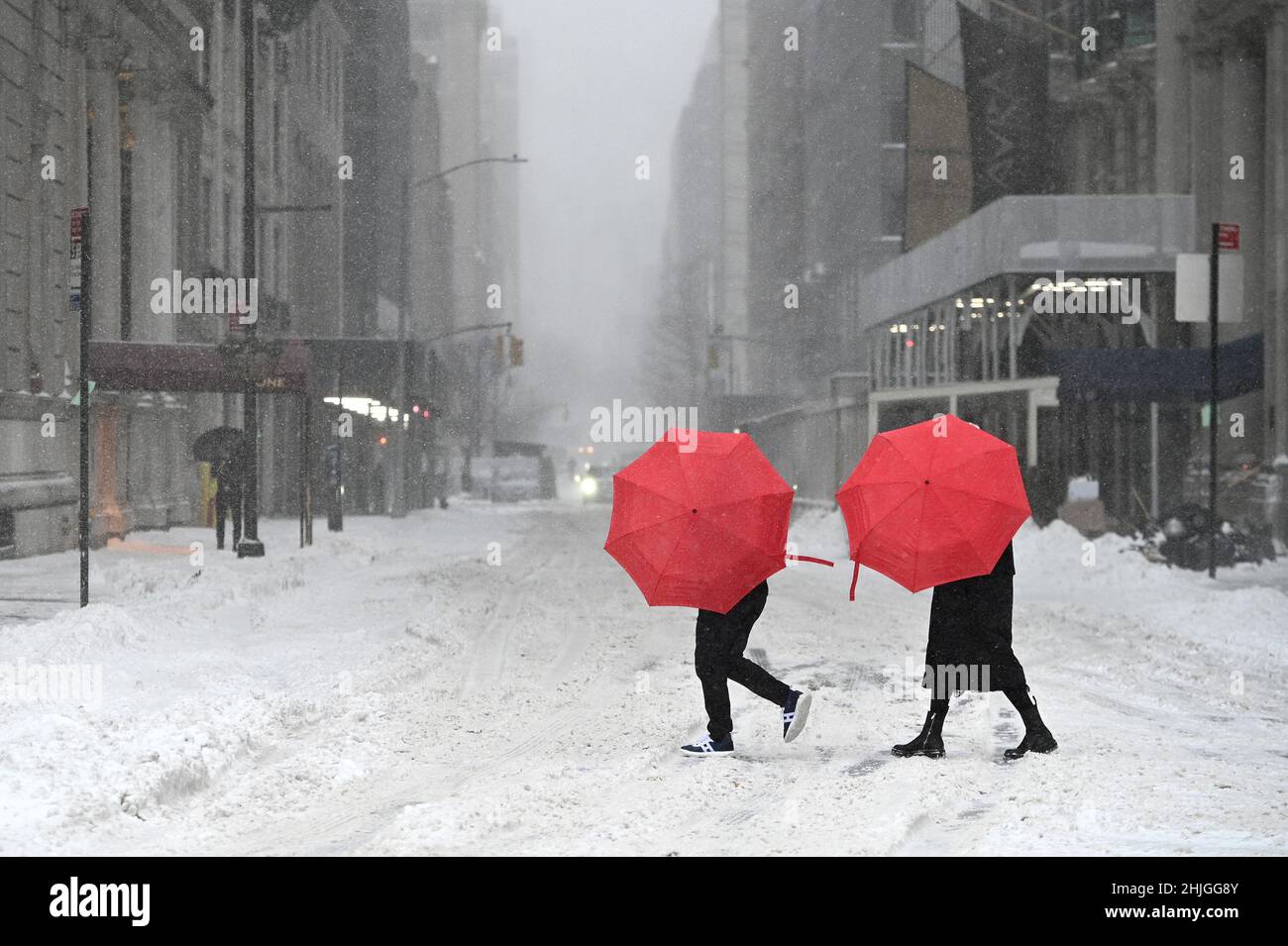 New York, USA. 29th Jan, 2022. Two people use red umbrellas to 