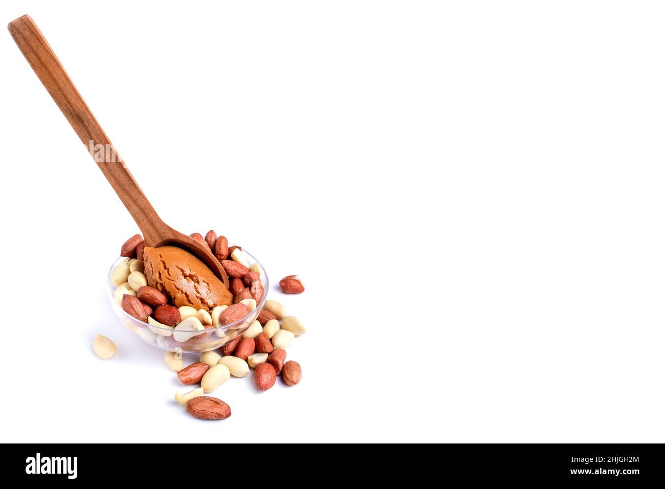 Peanuts with peanut paste in a wooden spoon. Isolated on a white background Stock Photo