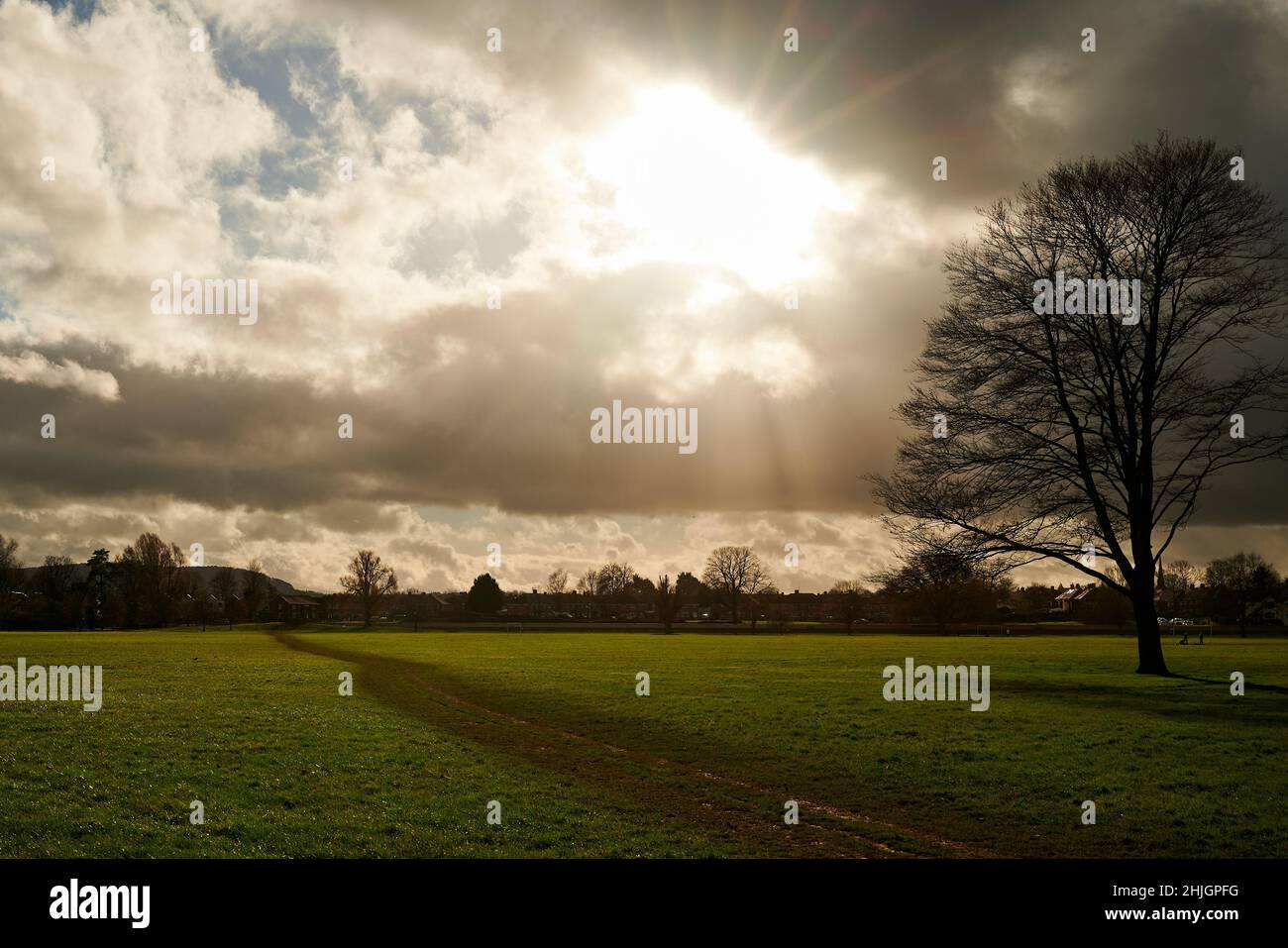 flat playing fields with muddy path under bright sun shining through clouds in winter Stock Photo