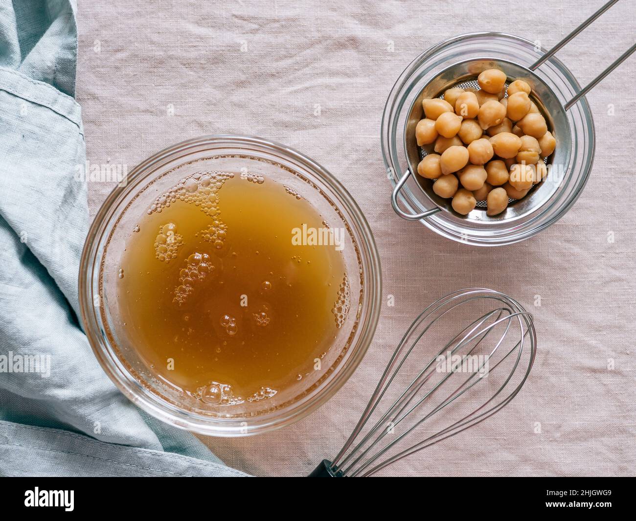Aquafaba in bowl over pink linen tablecloth. Chickpea water brine