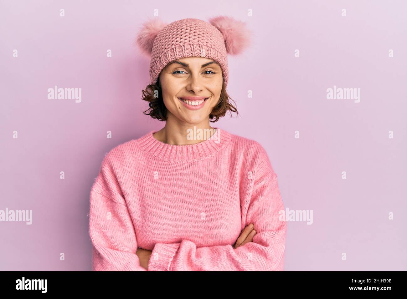 Young brunette woman wearing cute wool cap happy face smiling with crossed arms looking at the camera. positive person. Stock Photo