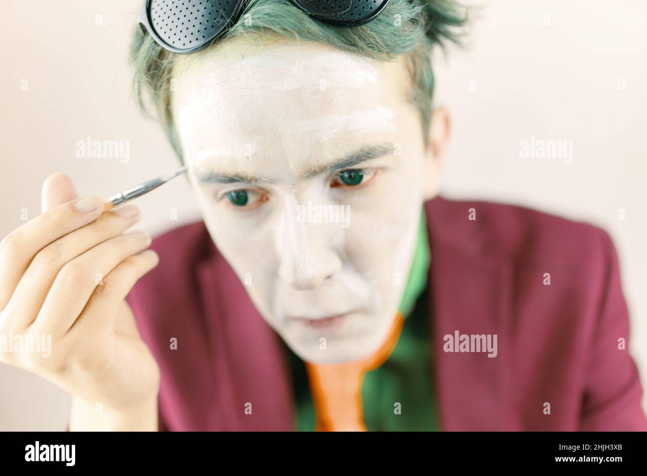 Cosplayer guy paints his face with brush Stock Photo Alamy