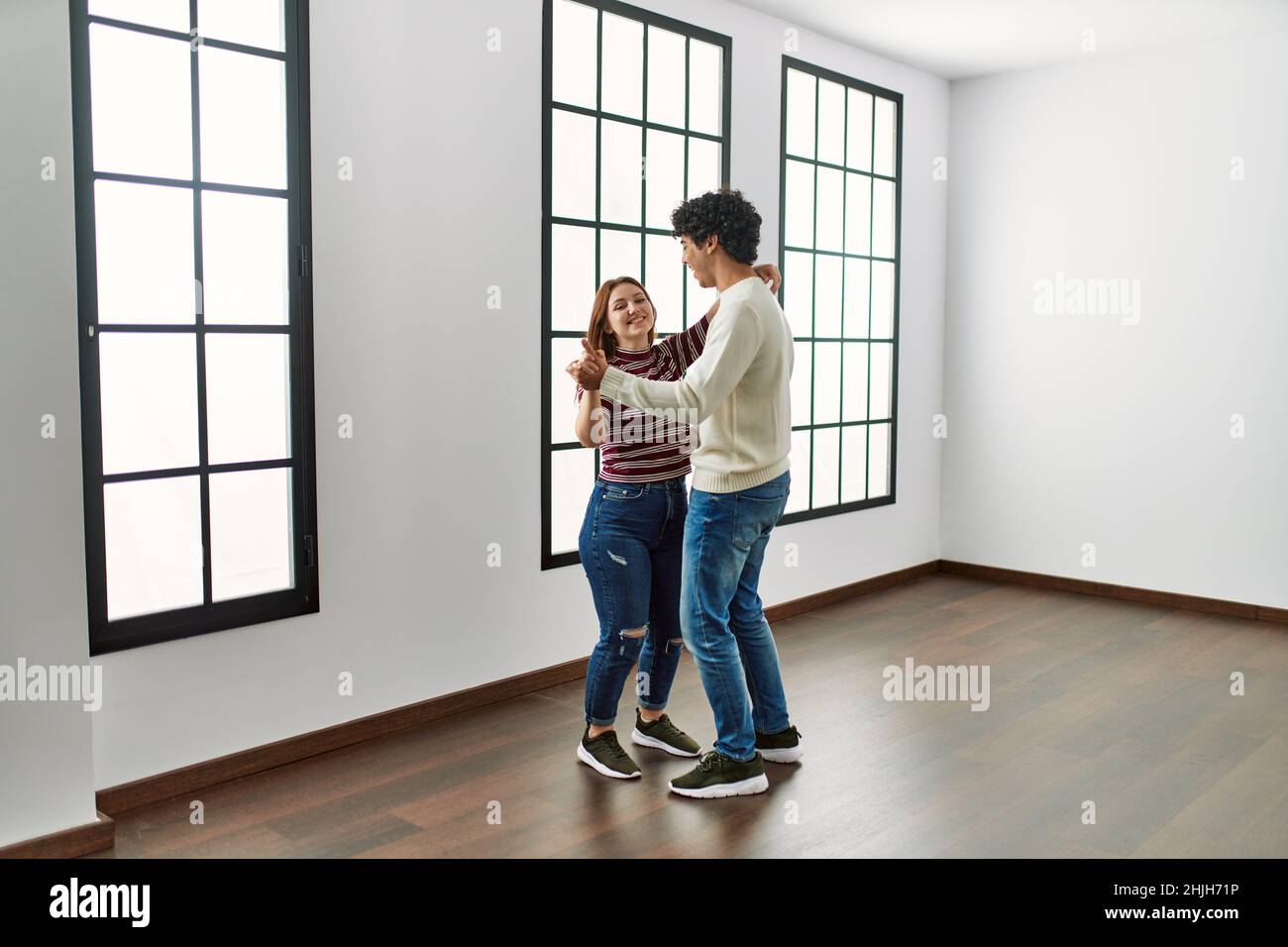 Young hispanic couple smiling happy dancing at empty new home Stock ...