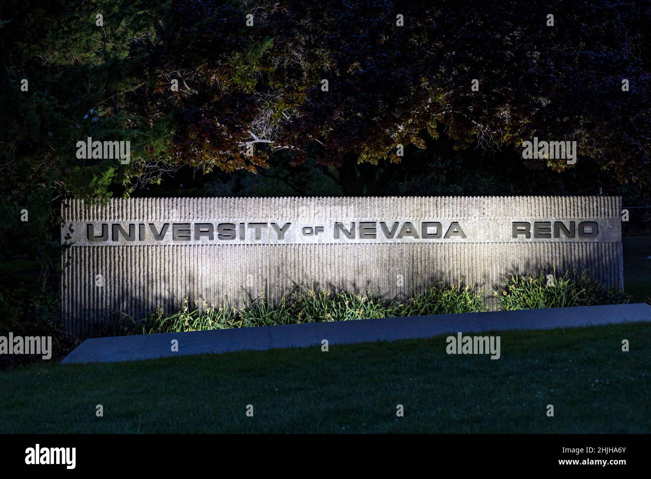 UNR University Nevada Reno campus sign at night lit with spotlights Stock Photo