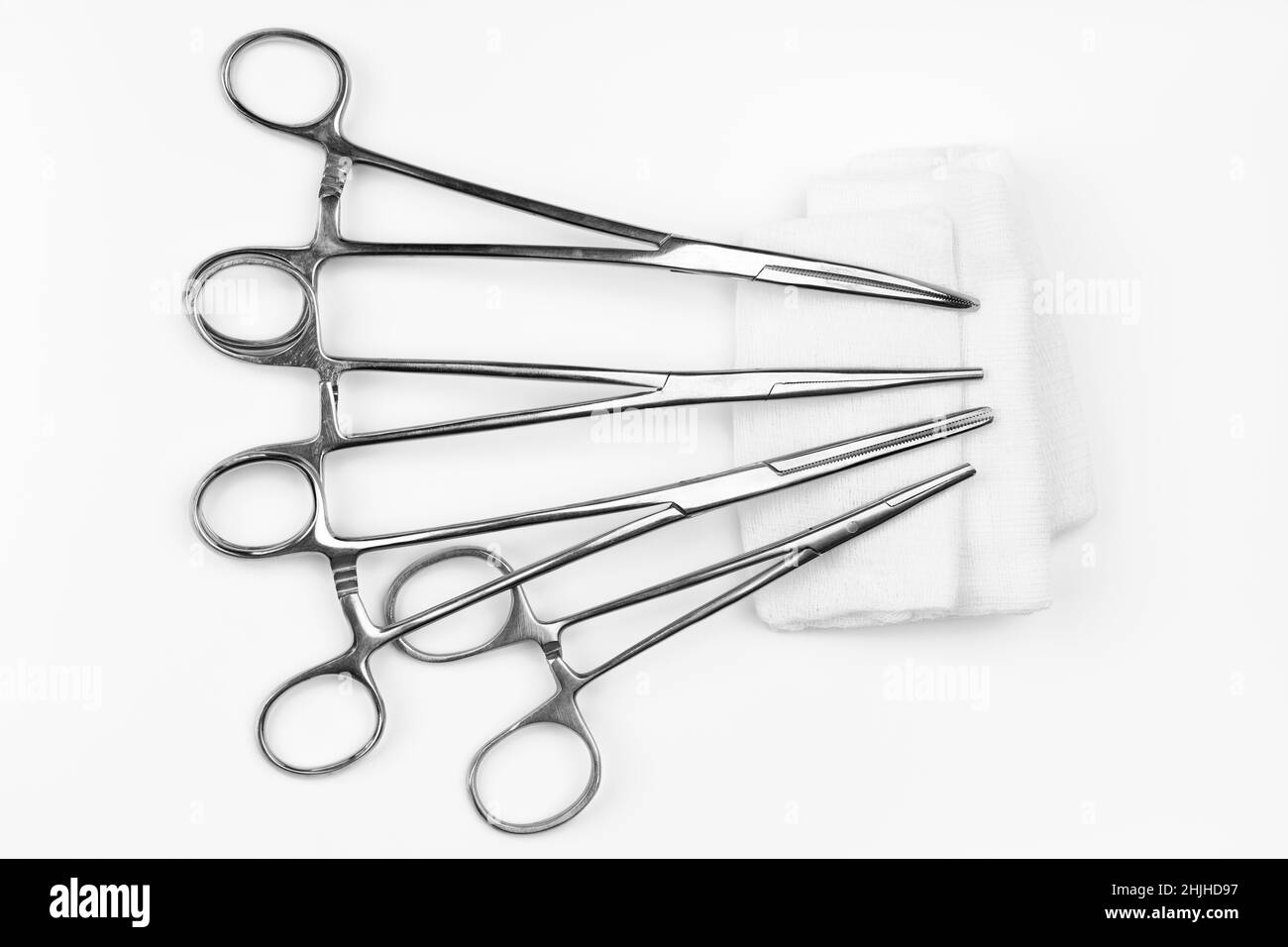 Lot of stainless surgical needle drivers lying on white sterile gauze swab. Medical instruments needle holders on white background Stock Photo