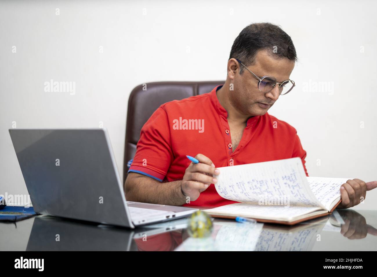 An Indian man in glasses with laptop computer working at an office Stock Photo