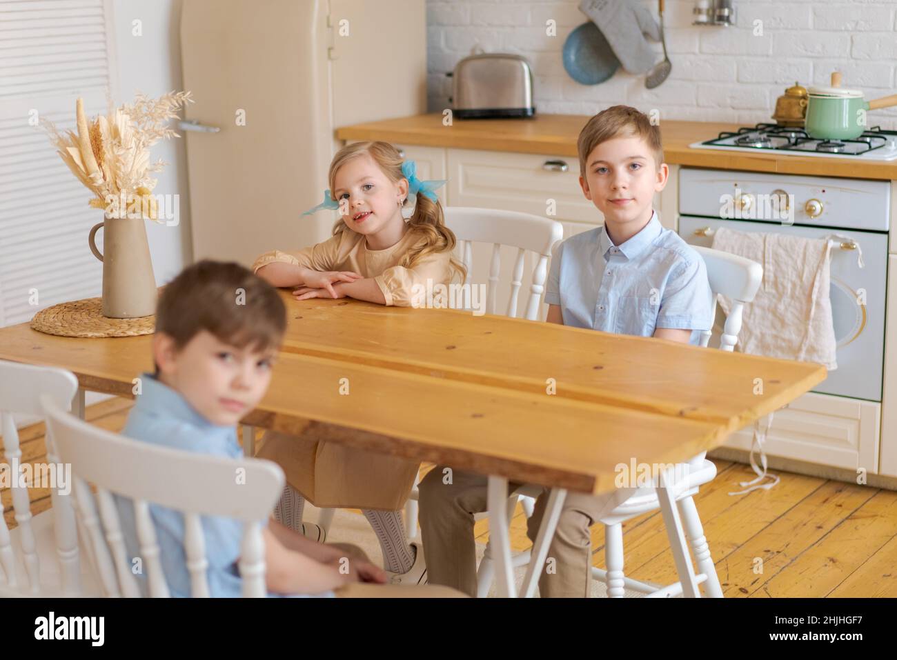 https://c8.alamy.com/comp/2HJHGF7/children-sit-at-table-in-kitchen-and-wait-for-their-parents-to-make-them-breakfast-or-lunch-when-mom-sets-the-table-happy-time-and-childhood-of-caucasian-school-children-2HJHGF7.jpg