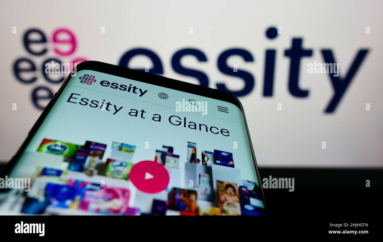Smartphone with website of Swedish consumer goods company Essity AB on screen in front of business logo. Focus on top-left of phone display. Stock Photo