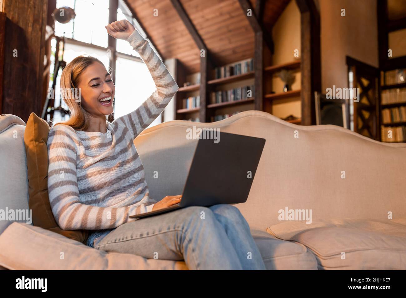 Excited woman using pc shaking clenched fist Stock Photo