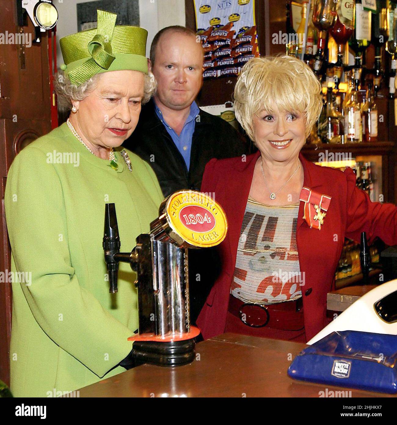 File photo dated 28/11/01 of Queen Elizabeth II (left) in the Queen Vic pub during a visit to Elstree Studios where EastEnders is filmed. She was accompanied by long standing cast member Barbara Windsor (Peggy Mitchell) and her on-screen son Steve McFadden (Phil Mitchell). Issue date: Sunday January 30, 2022. Stock Photo