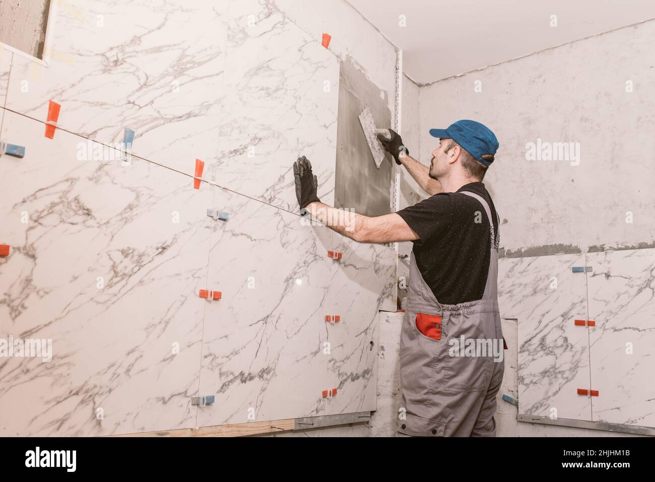 Tile Contractor Handyman instaling ceramic tiles on the bathroom wall Stock Photo - Alamy