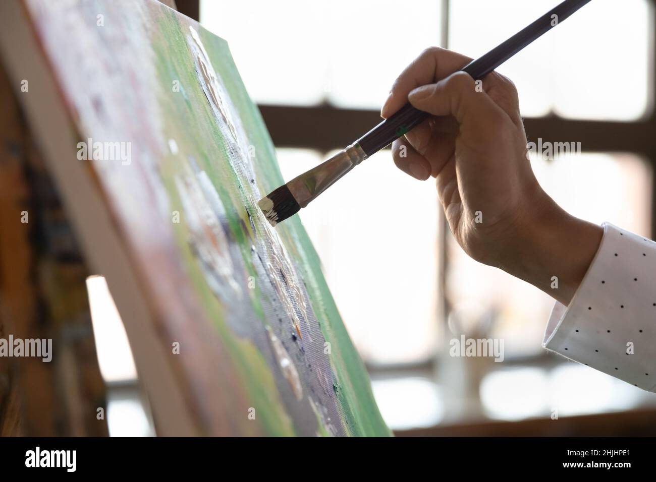 Painter hand holding paintbrush, touching canvas, putting strokes Stock Photo