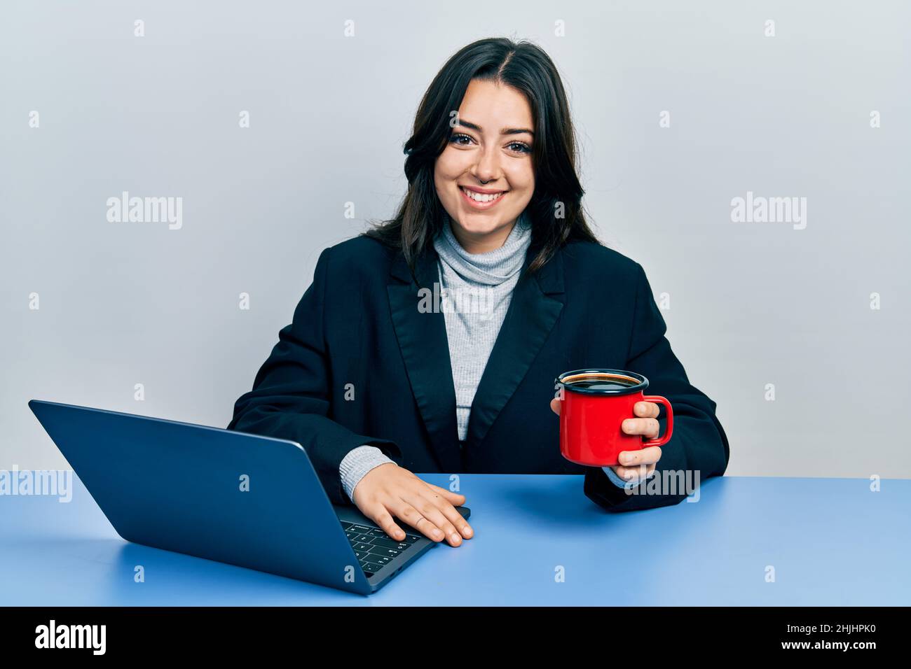 Beautiful hispanic business woman working at the office drinking a cup ...