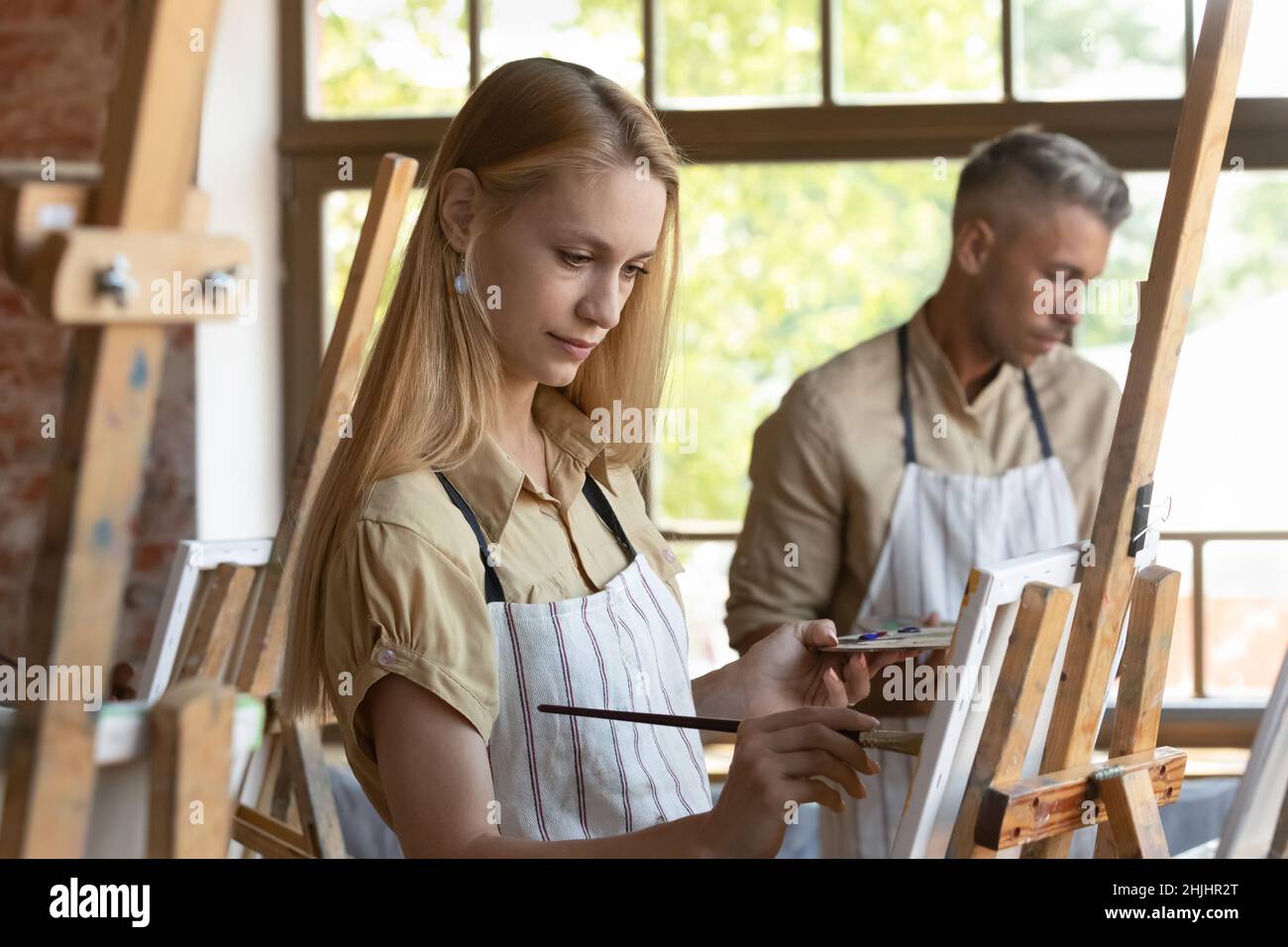 Young craft studio class student in apron drawing in paints Stock Photo