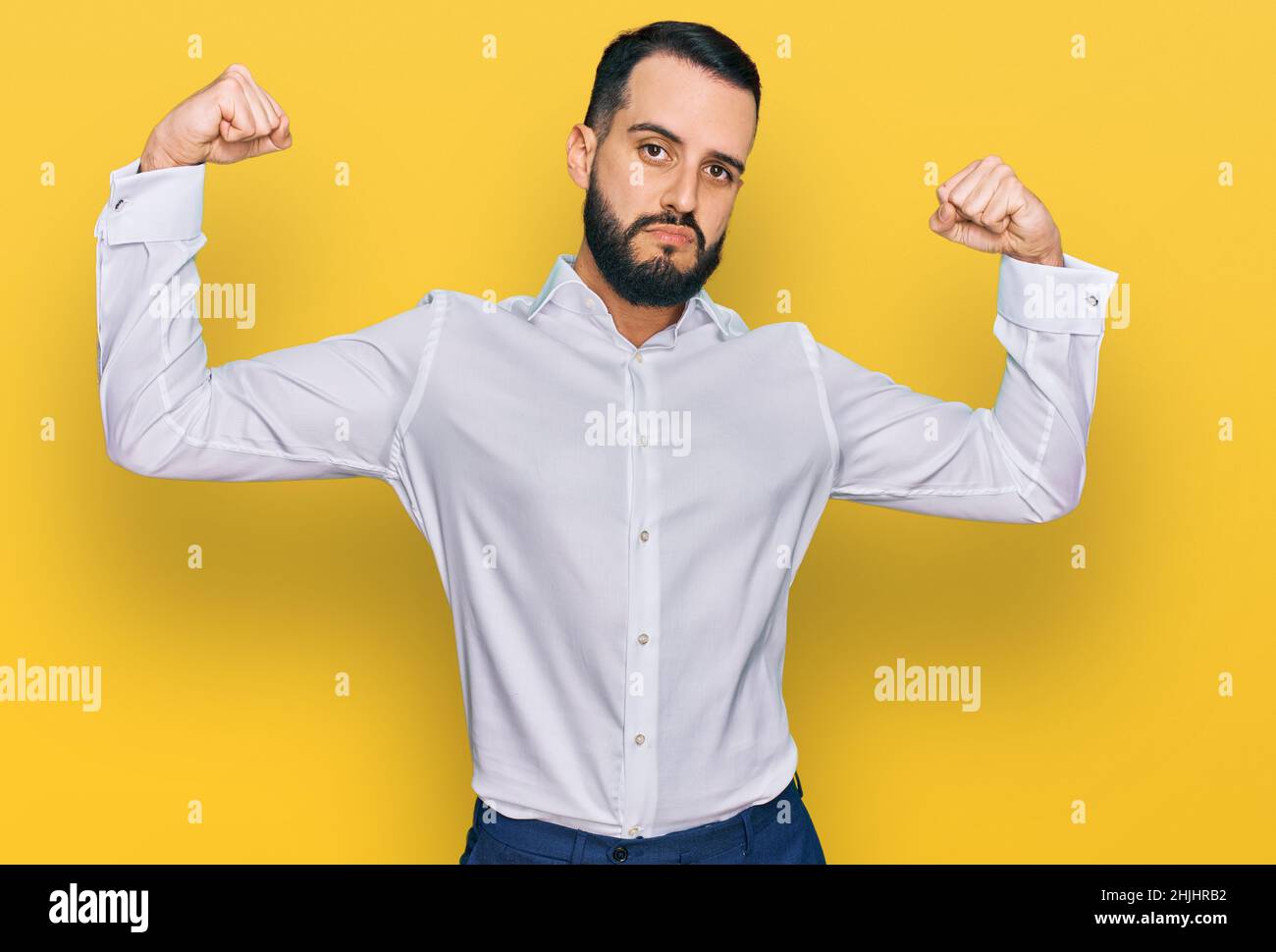 Young man with beard wearing business shirt showing arms muscles ...